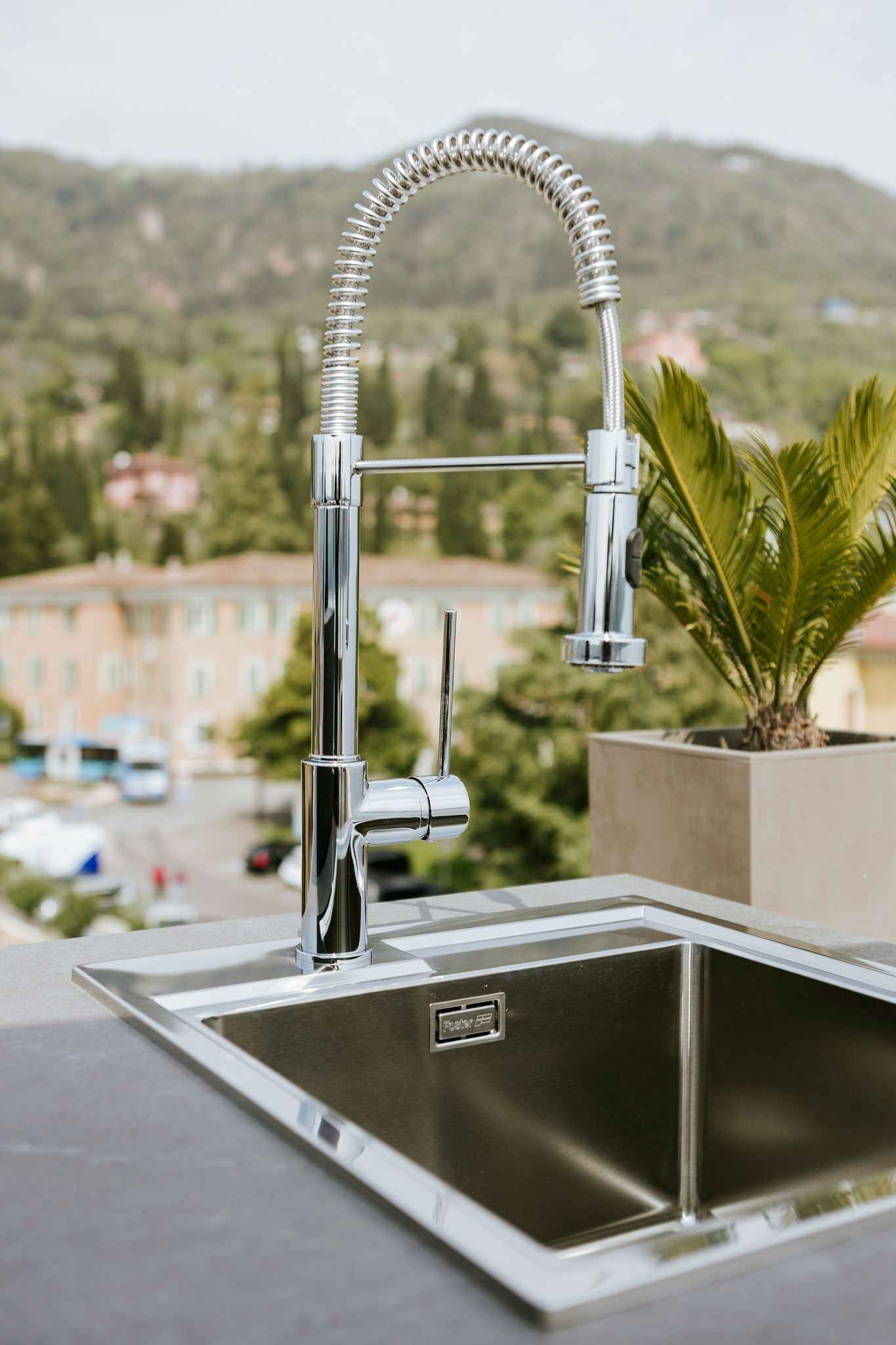 An outdoor kitchen sink with a sleek design and modern fixtures. The sink is nestled within a countertop and surrounded by the natural beauty of the outdoors. It exudes functionality and style, providing a convenient space for food preparation and clean-up in an outdoor culinary setting